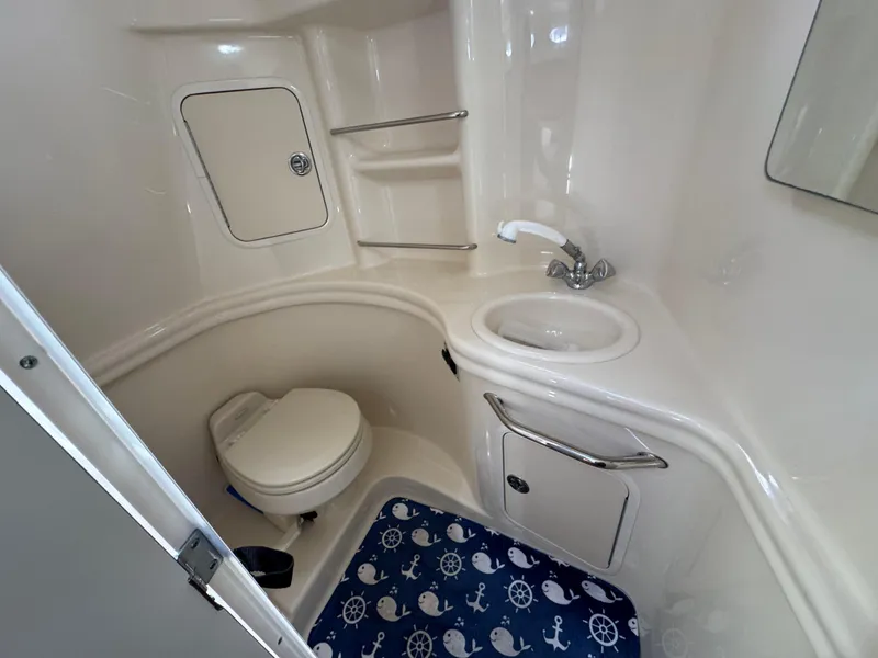Slide: The Image of 2005 Sea Ray 300 Sundancer bathroom with toilet, sink, and nautical-themed mat. - 14