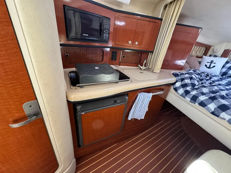 Slide: The Image of 2005 Sea Ray 300 Sundancer cabin with kitchenette, microwave, and cozy bed. - 4