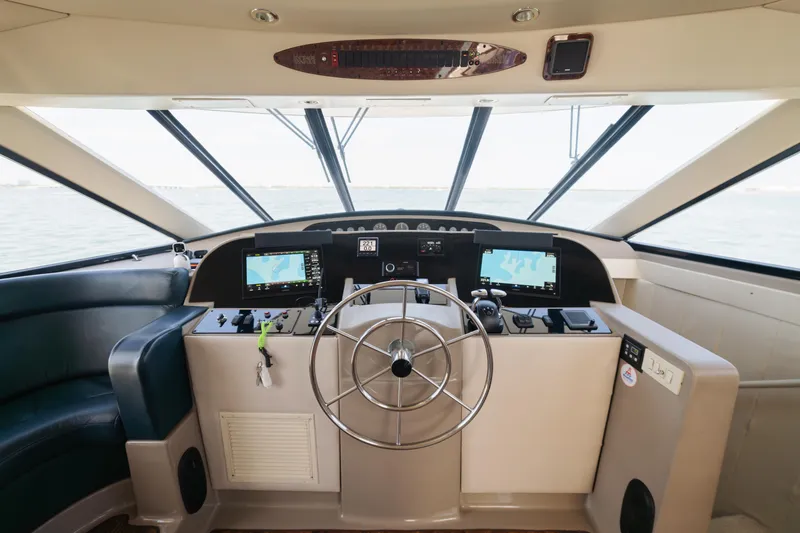 Slide: The Image of 1999 Bayliner 5788 yacht helm with steering wheel, navigation screens, and ocean view. - 26