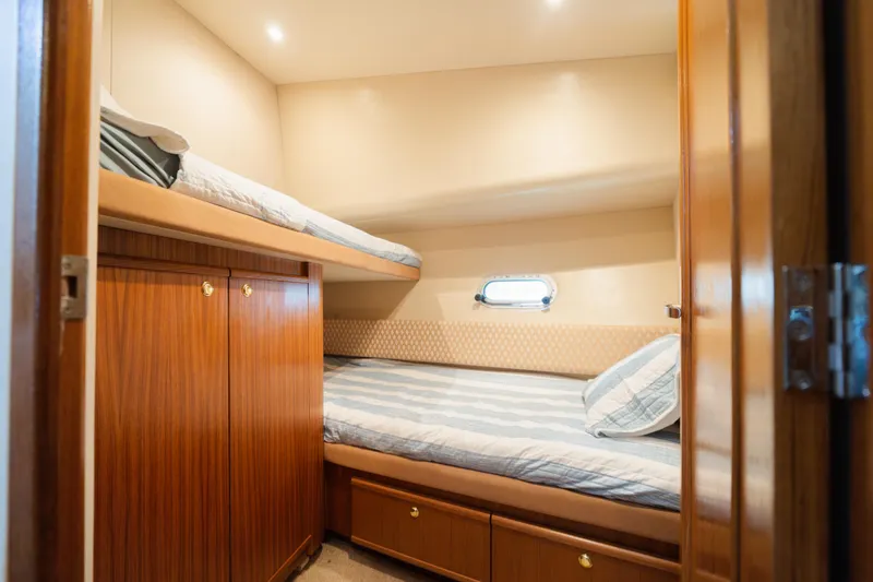 Slide: The Image of Cozy cabin with bunk beds in 1999 Bayliner 5788 yacht, featuring wood paneling and porthole. - 39