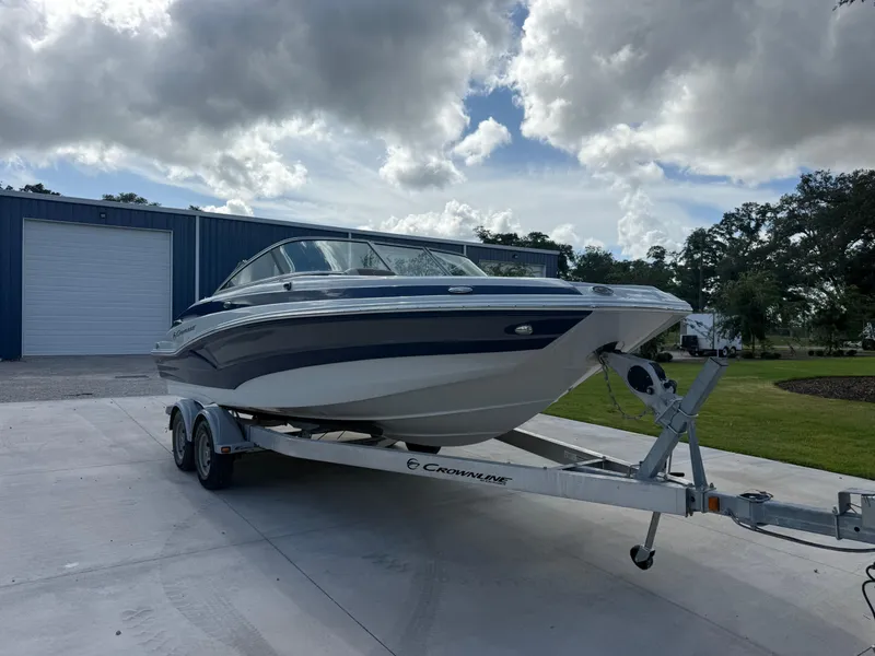 Slide: The Image of 2022 Crownline Eclipse E215 XS boat on trailer, parked outdoors. - 2