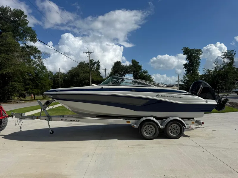 Slide: The Image of 2022 Crownline Eclipse E215 XS boat on trailer, parked outdoors under a blue sky. - 4