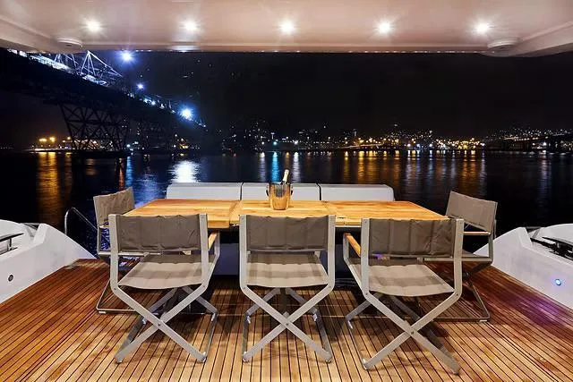Slide: The Image of Luxurious Schaefer 770 yacht deck with dining area, overlooking illuminated cityscape at night, 2026 model. - 29