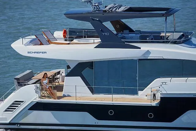 Slide: The Image of Luxury Schaefer 770 yacht cruising on water, 2026 model, with a person relaxing on deck. - 5