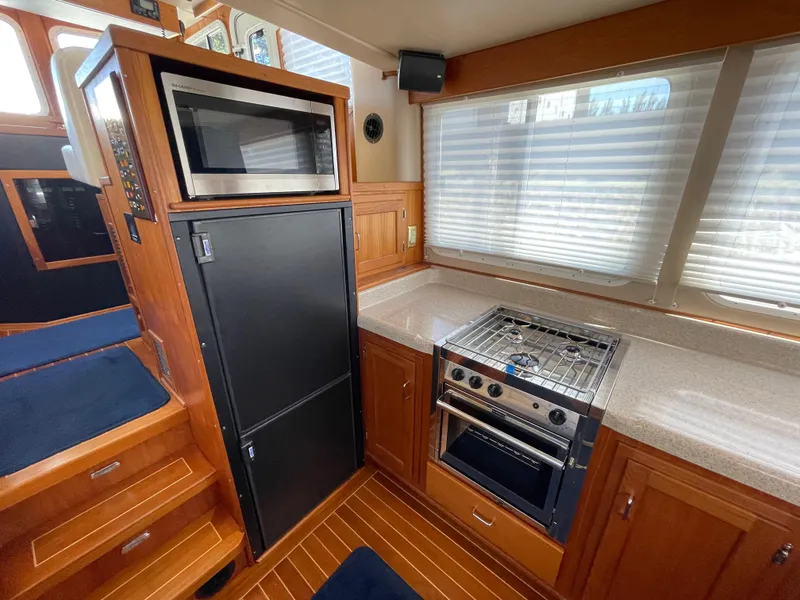 Slide: The Image of Interior of 2006 American Tug 34 featuring kitchen with stove, microwave, and wooden cabinetry. - 10