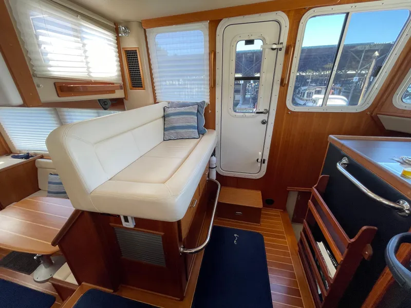 Slide: The Image of Interior of 2006 American Tug 34, featuring a cozy seating area and wooden accents. - 14