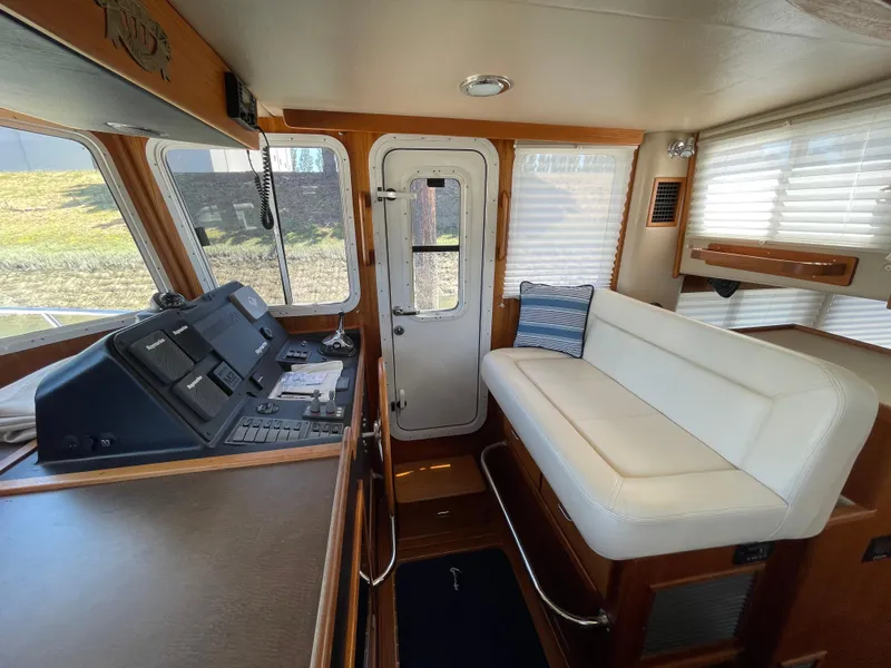 Slide: The Image of Interior of 2006 American Tug 34 with helm and white seating area. - 15
