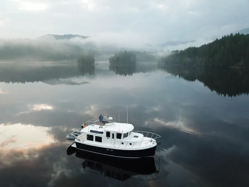 Slide: The Image of 2006 American Tug 34 on serene misty lake with forested background. - 2