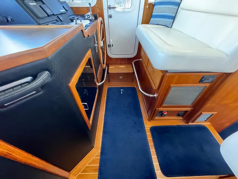 Slide: The Image of Interior of 2006 American Tug 34, featuring helm, seating, and wooden accents. - 23