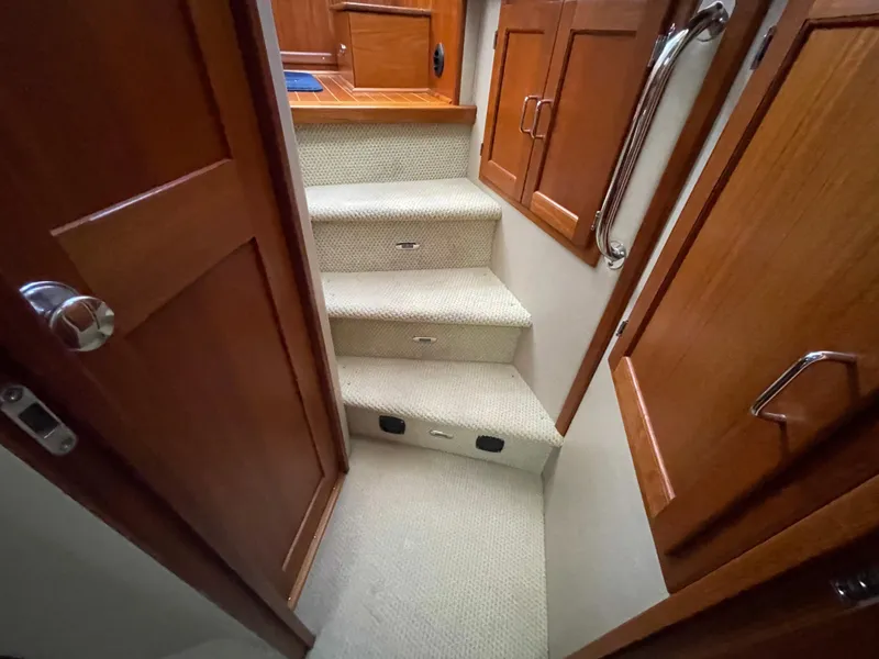 Slide: The Image of Staircase inside 2006 American Tug 34, featuring wooden cabinets and carpeted steps. - 33