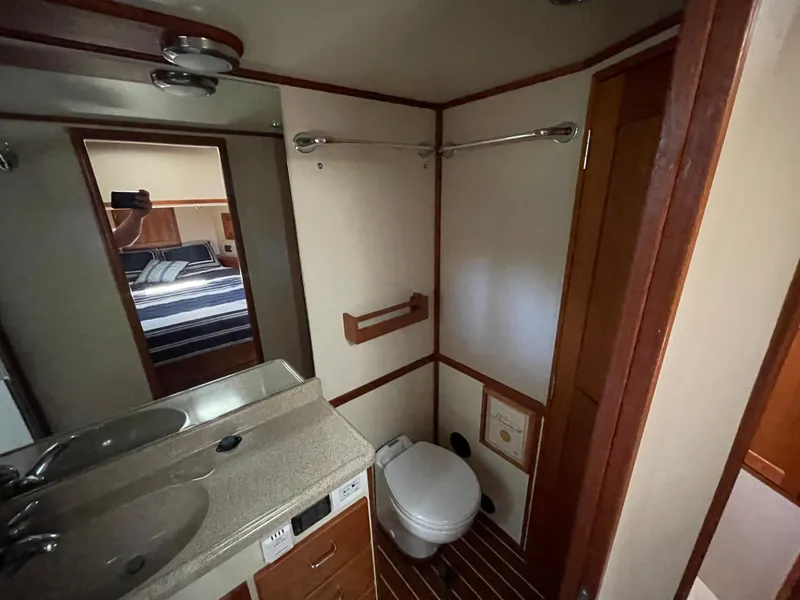 Slide: The Image of 2006 American Tug 34 bathroom with sink, toilet, and mirror reflecting bedroom. - 35