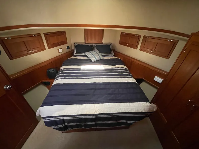 Slide: The Image of Cozy cabin interior of 2006 American Tug 34 with striped bedding and wooden storage cabinets. - 37