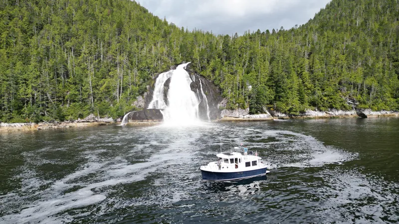 Slide: The Image of 2006 American Tug 34 cruising near a scenic waterfall surrounded by lush green forest. - 4