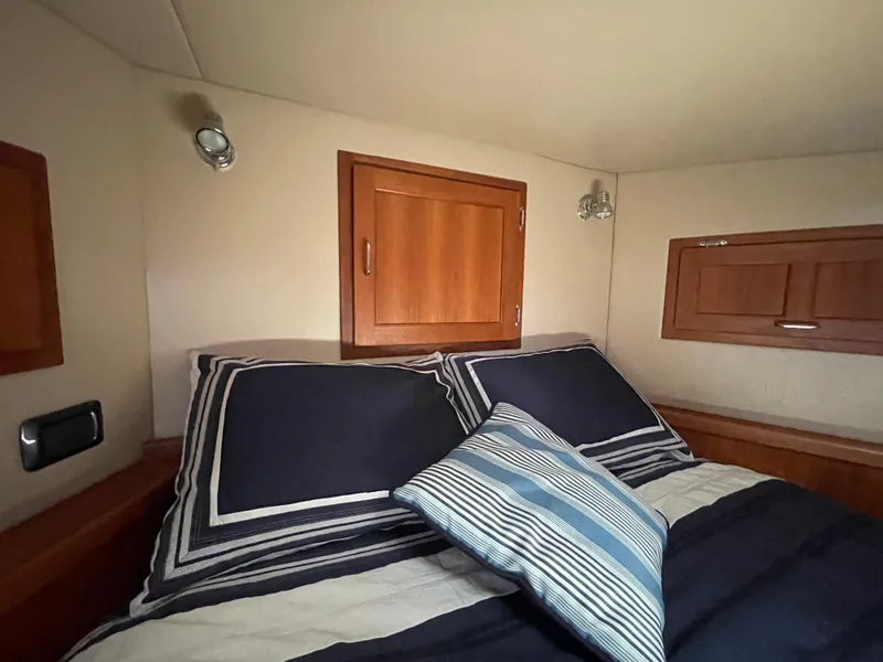 Slide: The Image of Cozy cabin bedroom in 2006 American Tug 34 with striped bedding and wooden storage cabinets. - 41