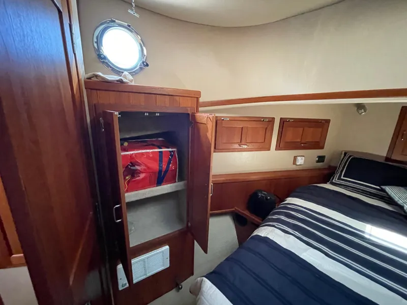 Slide: The Image of Cozy cabin interior of 2006 American Tug 34 with striped bedding and wooden storage. - 45