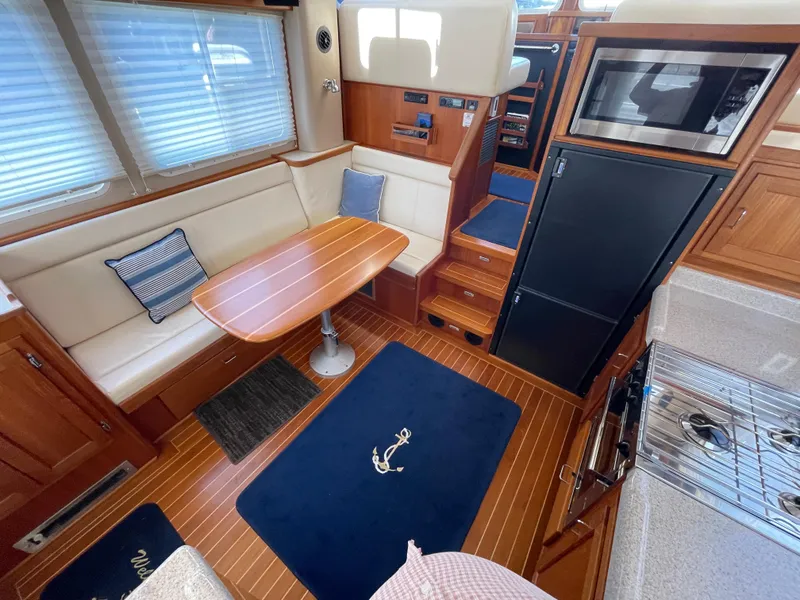 Slide: The Image of Interior of 2006 American Tug 34 with dining area, kitchen, and wooden flooring. - 8