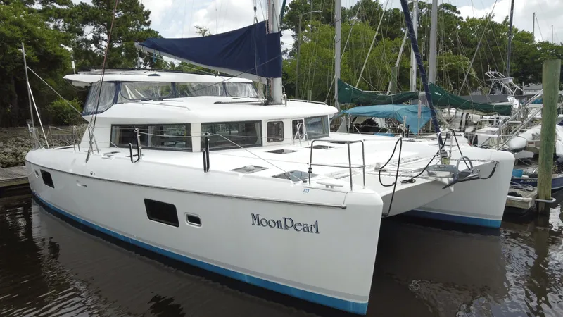 Slide: The Image of 2008 Lagoon 420 catamaran "Moon Pearl" docked at marina, surrounded by trees and boats. - 1