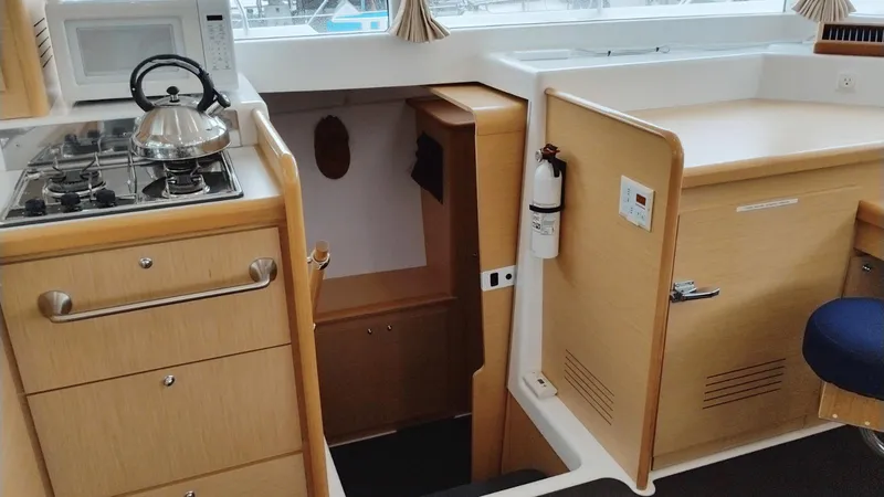 Slide: The Image of Interior of 2008 Lagoon 420 yacht kitchen with stove, microwave, and wooden cabinetry. - 14