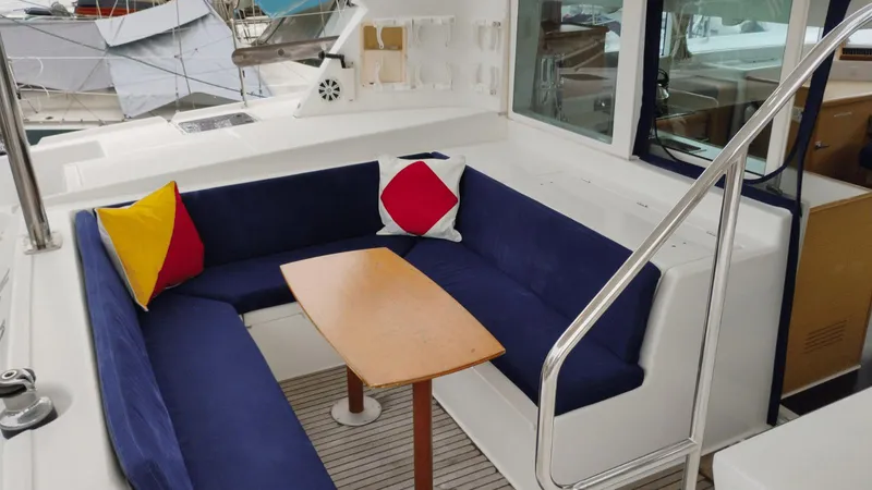 Slide: The Image of 2008 Lagoon 420 yacht interior with blue seating, colorful cushions, and wooden table. - 26