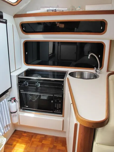 Slide: The Image of 1989 Tiara Yachts 3300 Open galley with stove, sink, and storage cabinets. - 5