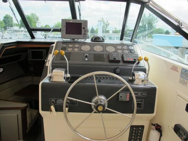 Slide: The Image of 1989 Tiara Yachts 3300 Open helm with steering wheel and navigation controls. - 6