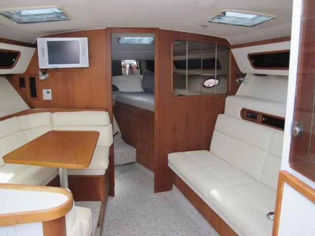 Slide: The Image of 1989 Tiara Yachts 3300 Open interior with wood finish, seating, and a small TV. - 8