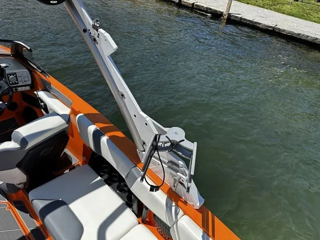 Slide: The Image of 2023 Malibu 21 LX boat interior with orange accents, docked by the water. - 10