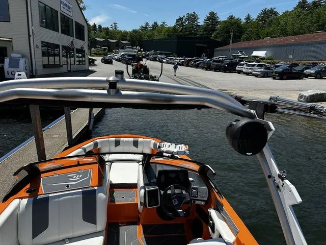 Slide: The Image of 2023 Malibu 21 LX boat docked at marina, featuring sleek design and vibrant orange accents. - 11