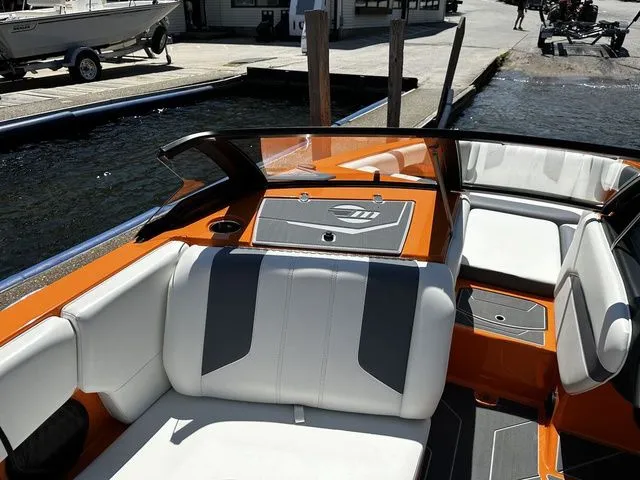 Slide: The Image of 2023 Malibu 21 LX boat with orange and white interior at a dock. - 12