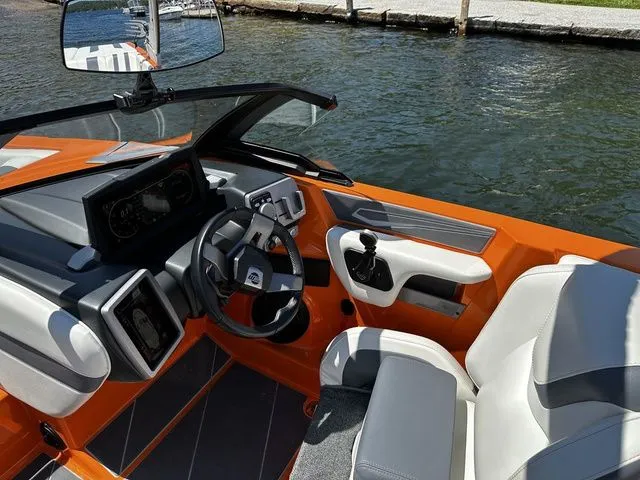Slide: The Image of 2023 Malibu 21 LX boat interior with orange and white seating, steering wheel, and dashboard. - 15