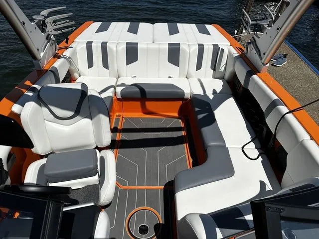 Slide: The Image of 2023 Malibu 21 LX boat interior with white and orange seating, docked by the water. - 17