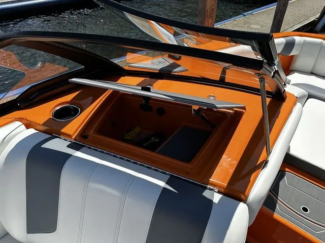 Slide: The Image of 2023 Malibu 21 LX boat interior with orange dashboard and open storage compartment. - 19