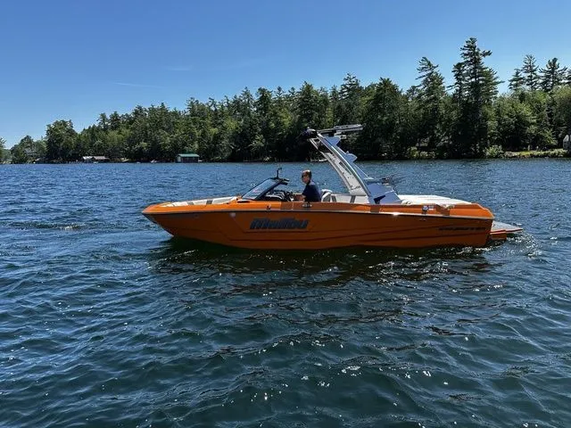 Slide: The Image of 2023 Malibu 21 LX boat on a lake with forested shoreline. - 3