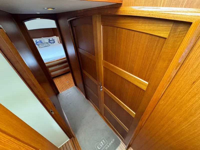 Slide: The Image of Wood-paneled hallway inside 2009 Grand Banks 45 Eastbay SX yacht, leading to a cozy bedroom. - 31