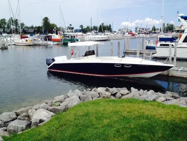 The Image of 1990 Donzi F-33 boat docked in a marina, surrounded by other boats and calm water. - 0