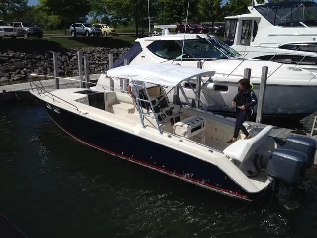 Slide: The Image of 1990 Donzi F-33 boat docked, featuring a canopy and dual outboard motors. - 1