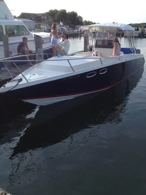 Slide: The Image of 1990 Donzi F-33 boat docked with people onboard, calm water, sunny day. - 2