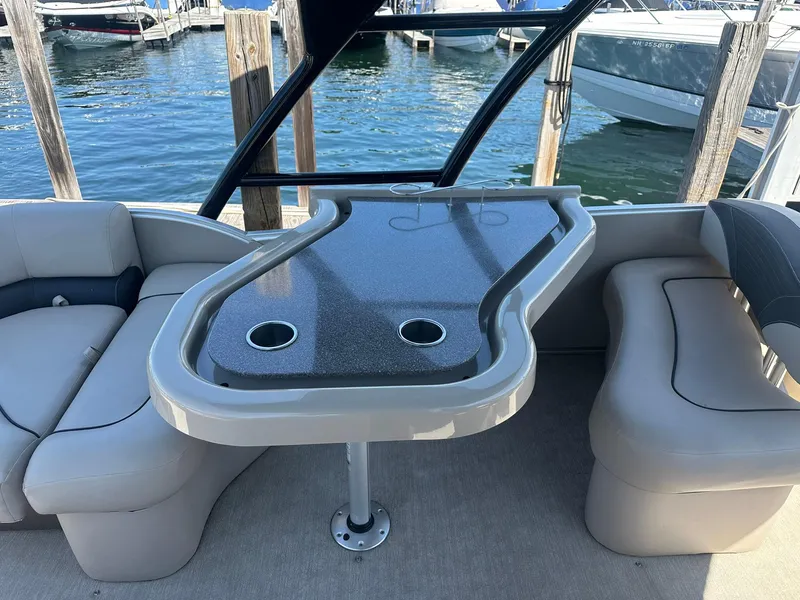 Slide: The Image of 2018 Avalon Catalina Platinum Entertainer boat interior with seating and table, docked by the water. - 10