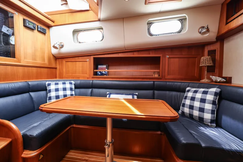 Slide: The Image of 2008 Grand Banks EASTBAY 39 SX interior with wooden table, blue seating, and checkered pillows. - 18
