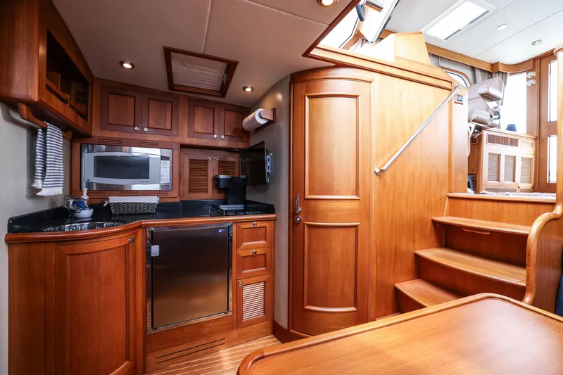 Slide: The Image of Luxurious 2008 Grand Banks EASTBAY 39 SX yacht interior with wooden cabinetry and modern kitchen amenities. - 24