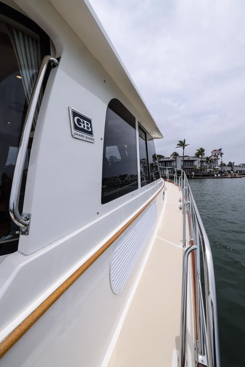 Slide: The Image of 2008 Grand Banks EASTBAY 39 SX yacht side view, docked near waterfront homes. - 4