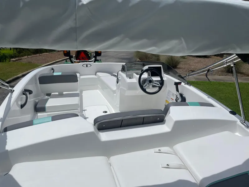 Slide: The Image of 2025 Tahoe T16 boat interior with seating and steering wheel, parked outdoors. - 3