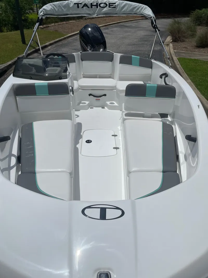 Slide: The Image of 2025 Tahoe T16 boat interior with seating and steering, parked on a paved path. - 4