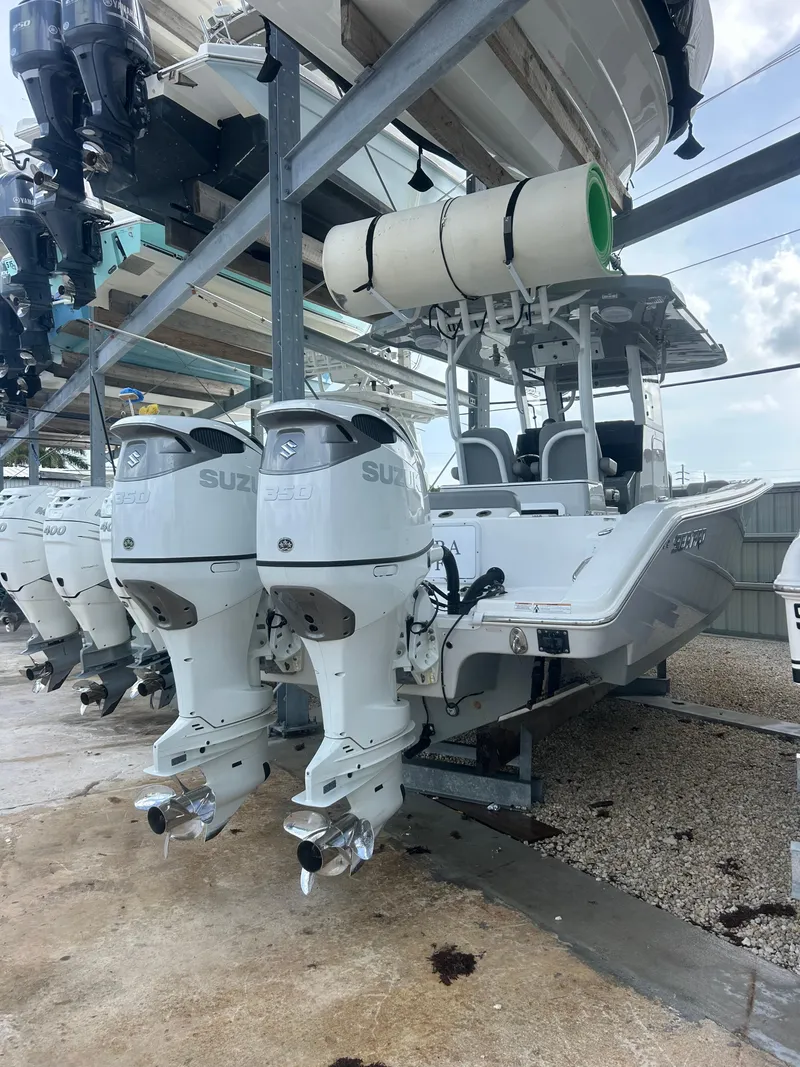 The Image of 2024 Sea Pro 320 DLX Center Console boat with dual Suzuki outboard engines in storage. - 1