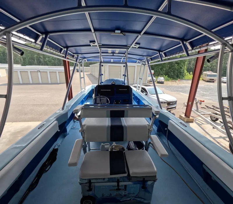 Slide: The Image of 2022 Eastward 30 boat interior with blue seating, overlooking calm waters and distant buildings. - 8