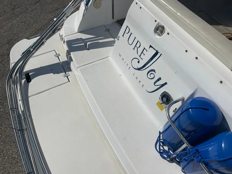 Slide: The Image of 1998 Cruisers 2870 Rogue boat with "Pure Joy" name, docked with blue fenders. - 12