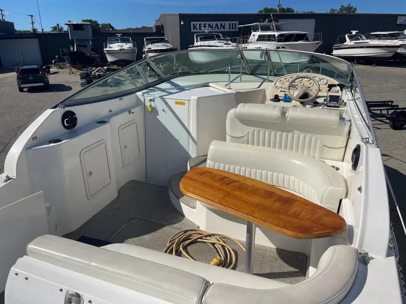 Slide: The Image of 1998 Cruisers 2870 Rogue boat interior with seating and wooden table, docked at a marina. - 13