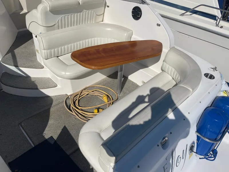 Slide: The Image of 1998 Cruisers 2870 Rogue boat interior with white seating, wooden table, and coiled rope. - 14