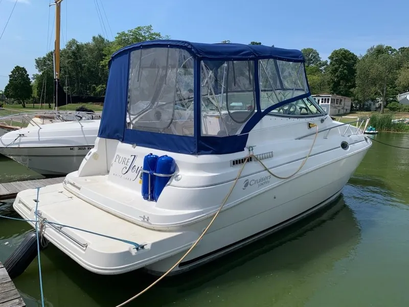 Slide: The Image of 1998 Cruisers 2870 Rogue boat docked with blue canopy and "Pure Joy" text. - 2