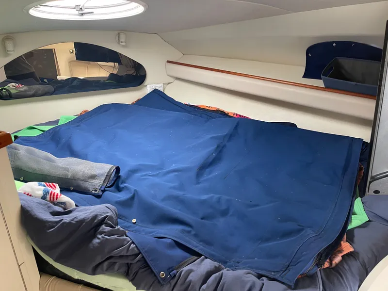 Slide: The Image of 1998 Cruisers 2870 Rogue cabin interior with bed, blue cover, and porthole window. - 26